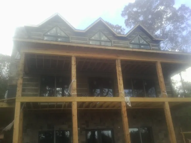 Dormers and porch framing on a large log home under construction — Roof Coating work by our crew in Little Sioux