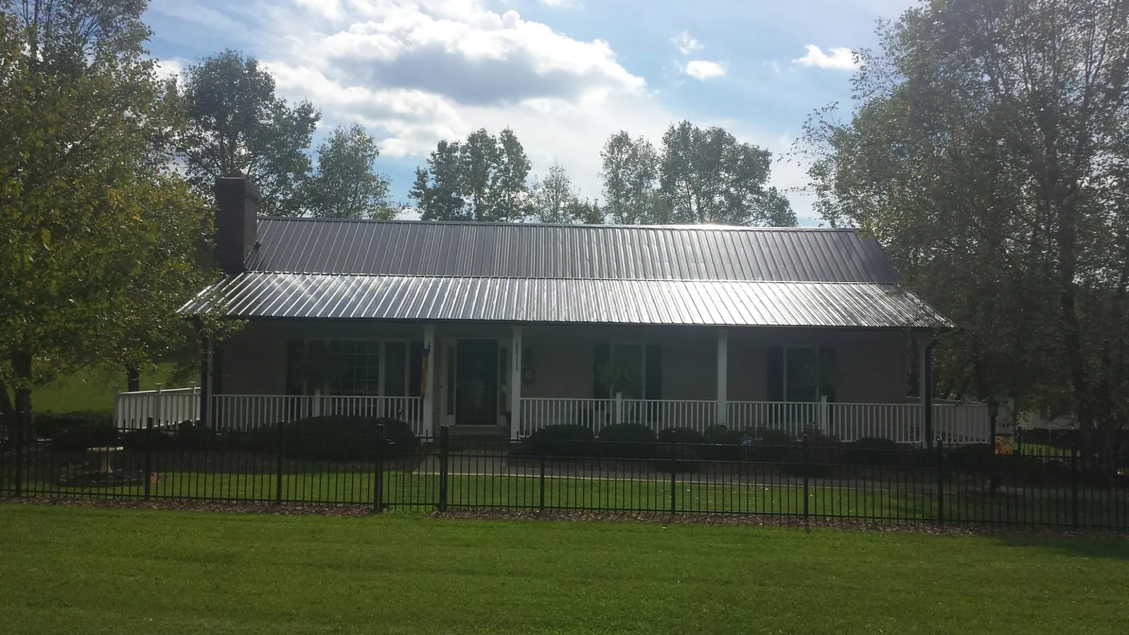 Gray metal roof on a brick ranch with a full width front porch — Gutter Guard Installation work by our crew in Little Sioux