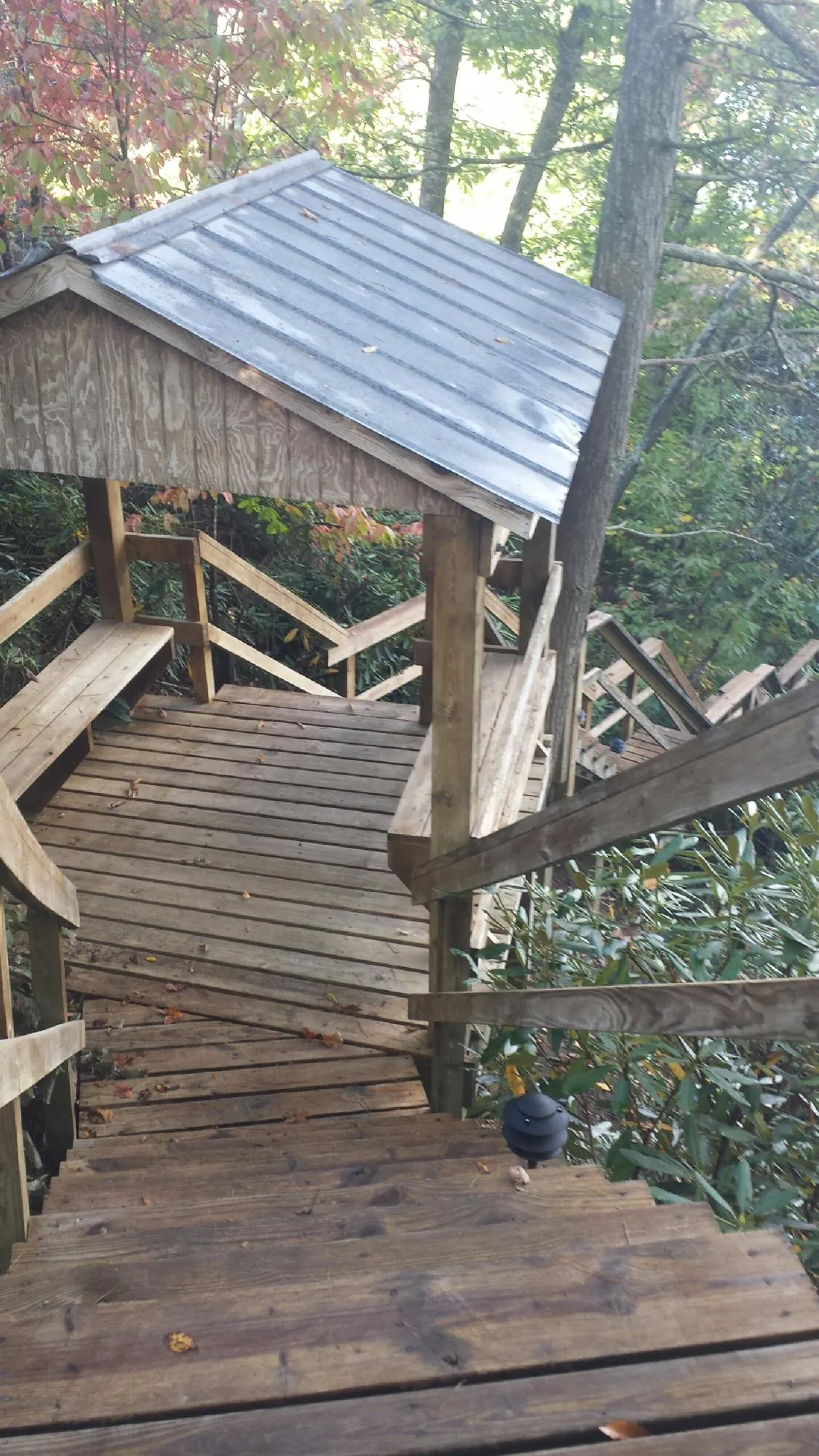 Metal roofed shelter over wooden steps on a wooded walkway — Skylight Repair & Installation work by our crew in Little Sioux