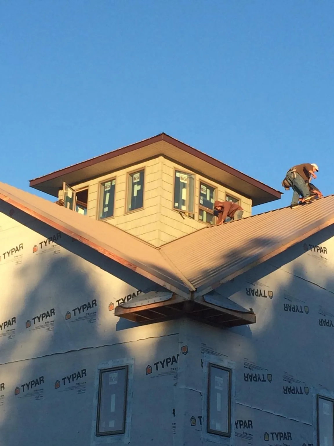 Roofers working around a rooftop cupola on a new metal roof at sunset — Roof Waterproofing in Little Sioux by Roofing Brothers